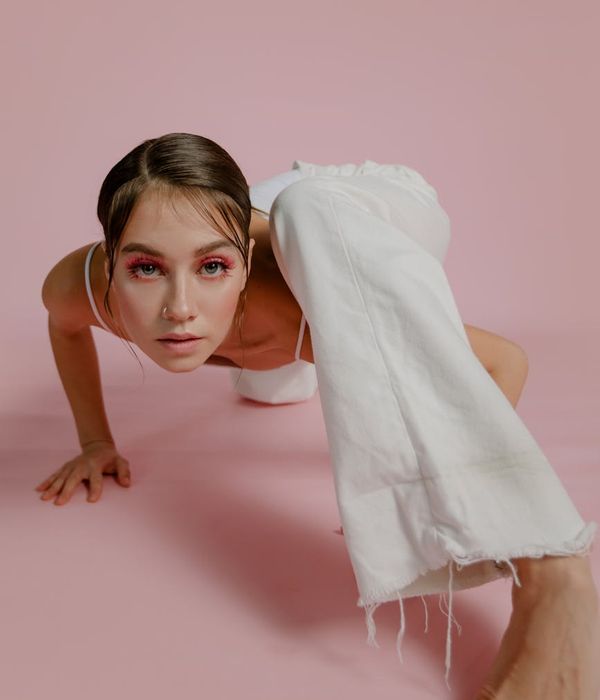 Woman in an energetic warrior yoga pose against a minimal background.